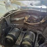Close-up inside an opened engine housing with oil residue, two cylindrical parts and a bracket
